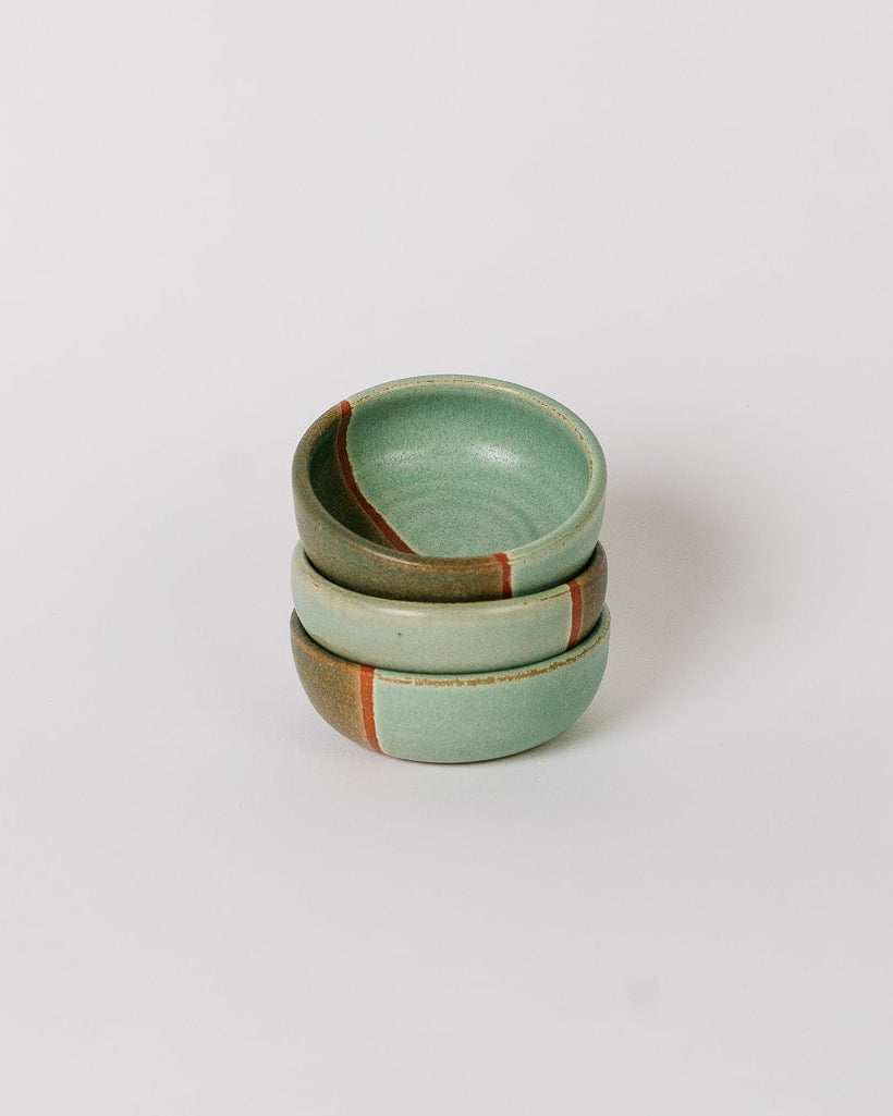Stack of three green ceramic bowls on a white background