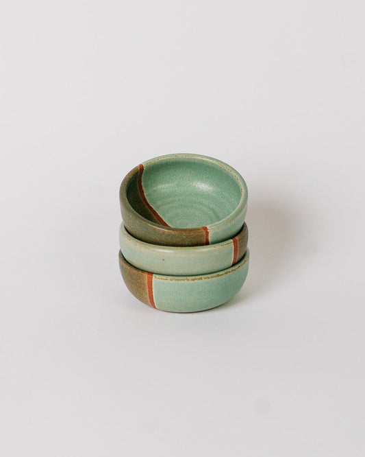 Stack of three green ceramic bowls on a white background